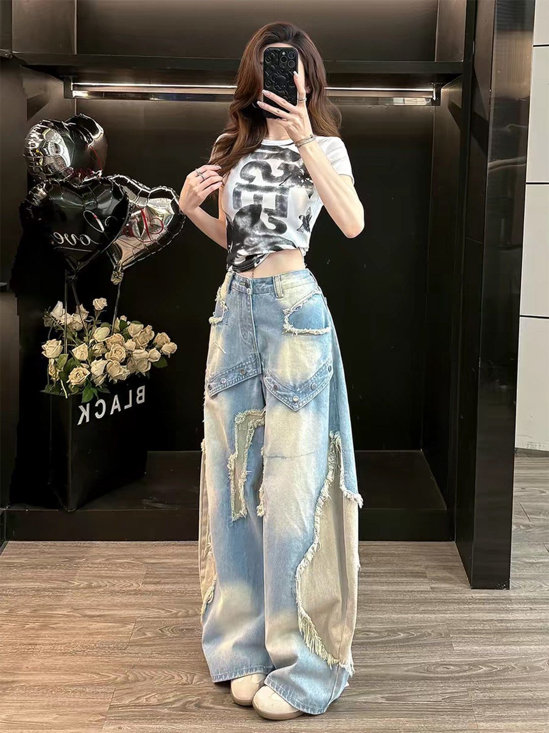 Light washed blue wide leg baggy jeans with frayed patch appliques worn by a woman, full length front view