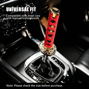Red katana style shift knob fitted on a manual gear stick inside a car cabin