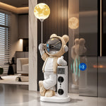 Beige astronaut bear statue with a glowing moon lamp, speaker tower and temperature display in a modern hallway
