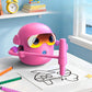 Pink drawing robot outlining an airplane on paper with color pens on the desk
