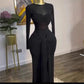 Black long sleeve maxi dress on a mannequin with twisted bust band and draped front tie beside a plant