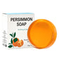 Close view of an amber persimmon soap bar beside the edge of a Persimmon Soap box with a persimmon illustration
