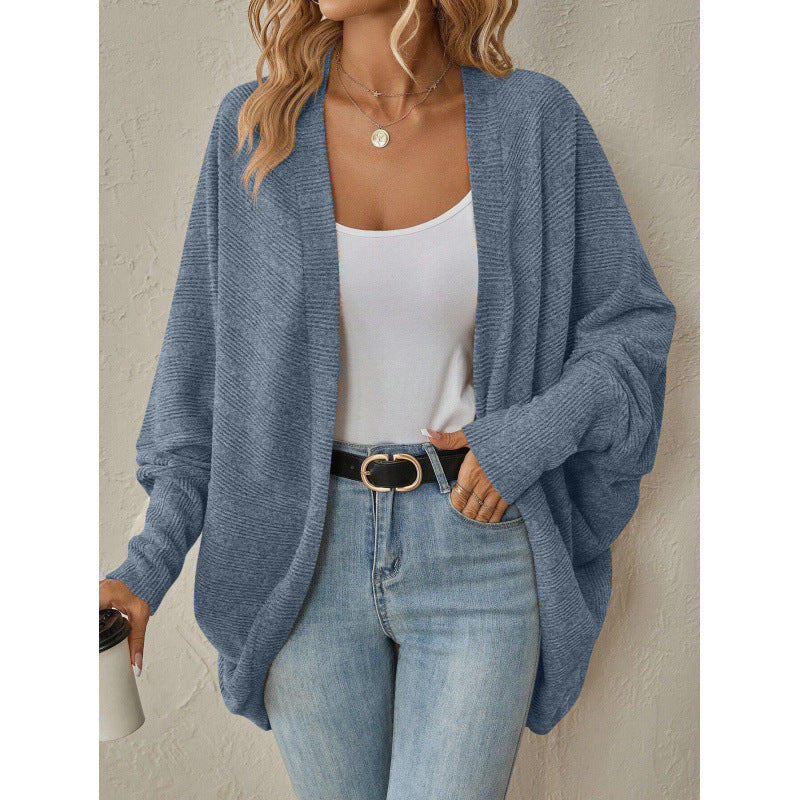 Woman wearing a pink open front knit cardigan over a white top and jeans