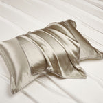 Champagne mulberry silk pillowcase with a contrast piped edge draped on a white bed