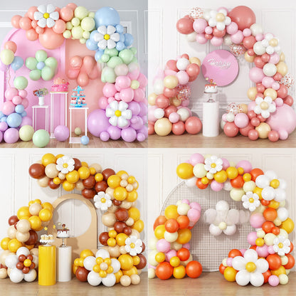 Macaron balloon garland with white daisy flowers arched above a dessert table