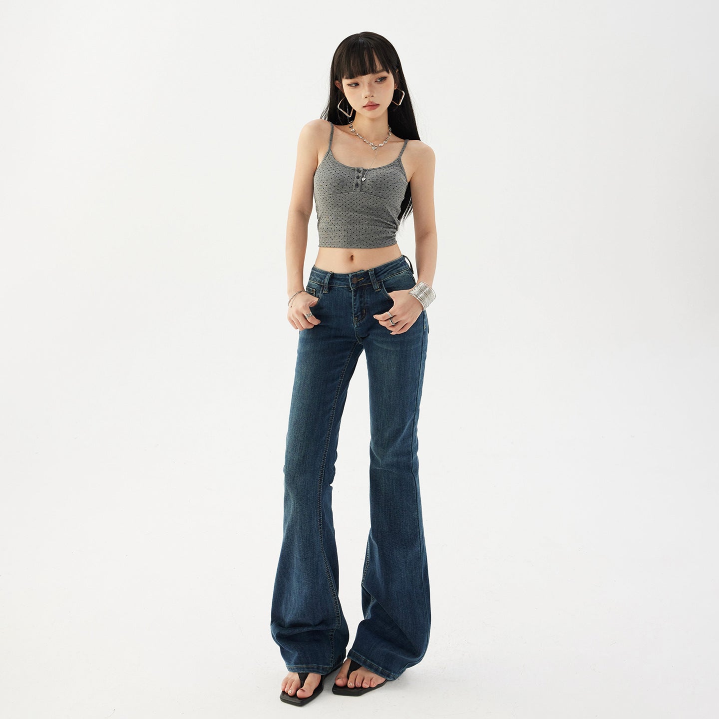 Womens low rise flared dark wash denim jeans on a model, full length front view with flat sandals