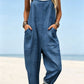Size XL option: Denim blue overalls with an embossed flower texture, cuffed legs and pockets on a beach