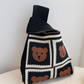 Jacquard knit wrist bag shown from the front with its loop handle upright