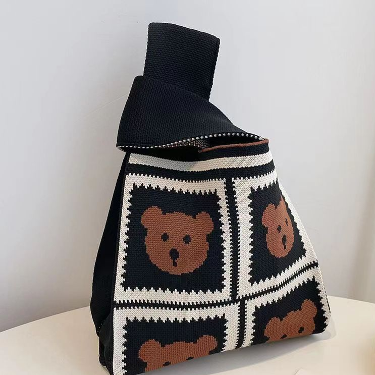 Jacquard knit wrist bag shown from the front with its loop handle upright