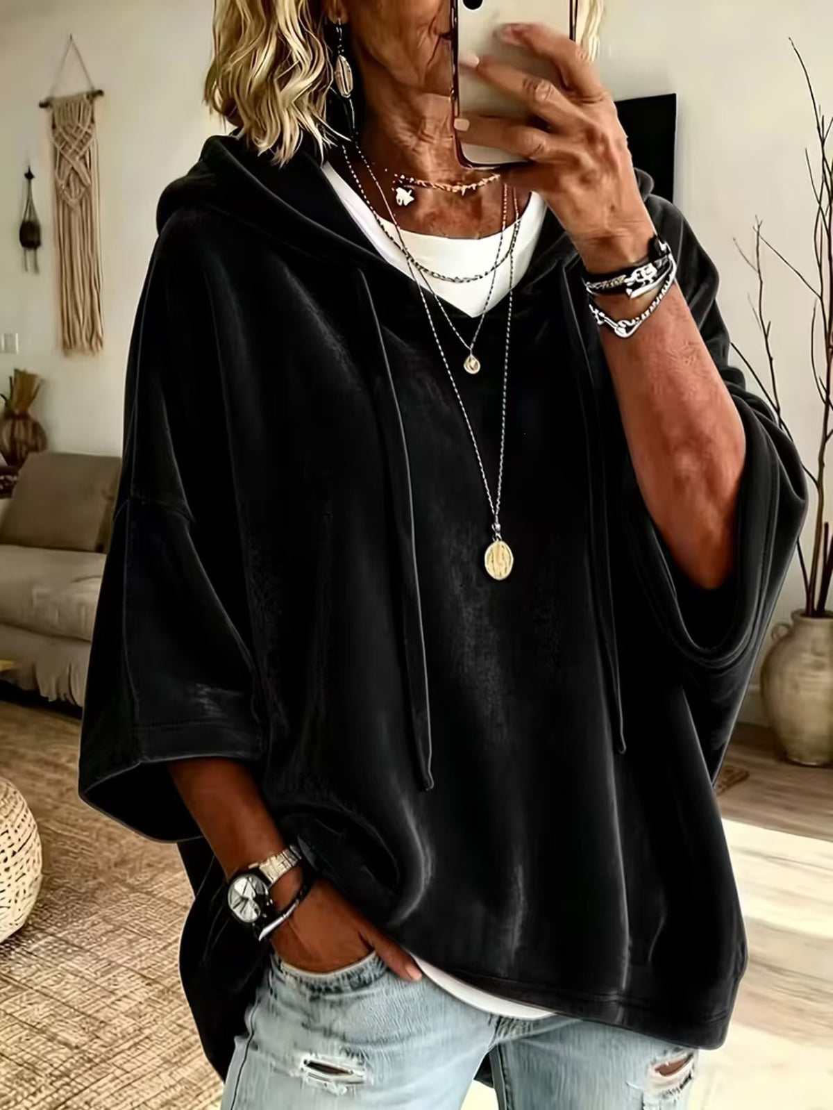 Loose womens hooded top with a drawstring hood shown on a model indoors