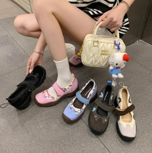 Woman seated on the floor with the platform shoes in black, pink, blue, gray brown and greige beside a cream handbag