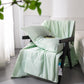 Summer coverlet draped over an armchair arm, pale grey reverse turned up at the fold