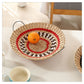 Round woven straw wall ornament in black and natural tones with a zigzag weave