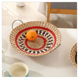 Round woven straw wall ornament in black and natural tones with a zigzag weave