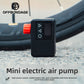 Black mini electric air pump with red knob, three buttons and LED screen standing on gravel in front of a bicycle tire