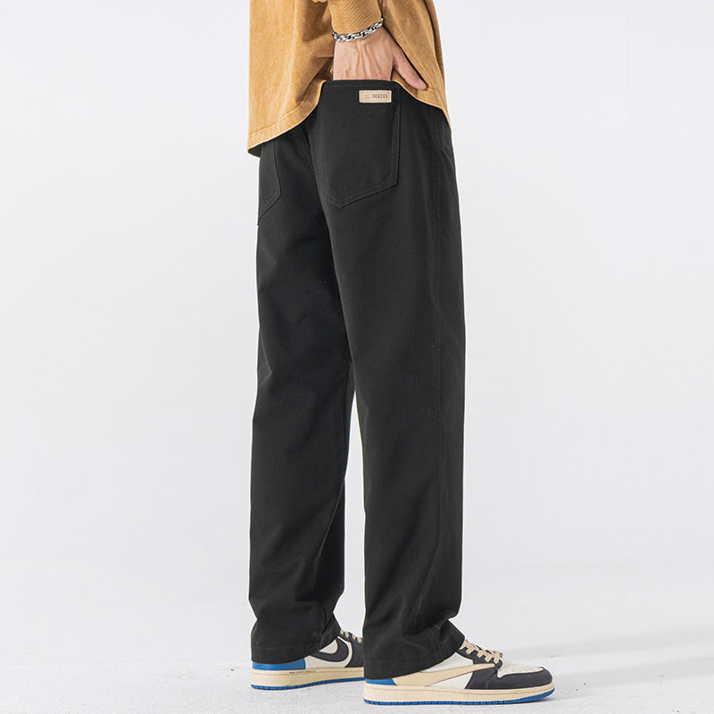 Black straight leg cotton pants in size 4XL, side view with a hand in the pocket and low sneakers