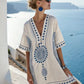 Loose V neck bohemian beach cover up dress in a blue and orange sun motif print, worn by the pool on a warm afternoon