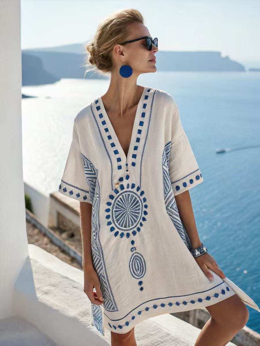 Loose V neck bohemian beach cover up dress in a blue and orange sun motif print, worn by the pool on a warm afternoon