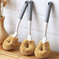 Coconut fiber brush scrubbing a pot at the kitchen sink