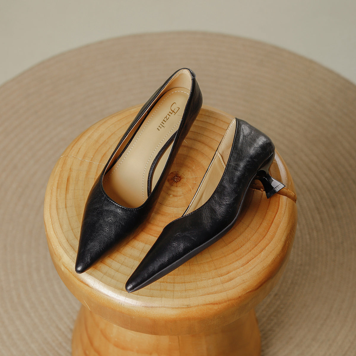 Pair of black pointed toe pumps with a low flared heel on a wooden stool, Black option, size 38