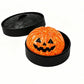 Orange pumpkin face squishy dumpling toy inside a black steamer basket
