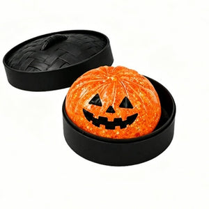 Orange pumpkin face squishy dumpling toy inside a black steamer basket