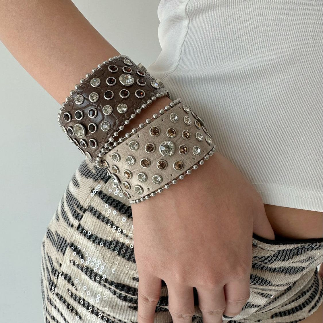 Punk rhinestone leather cuff bracelets in dark and light colors stacked on a wrist