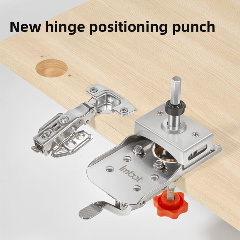 Stainless steel hinge positioning punch on a light wood board beside a concealed cabinet hinge and drill bit