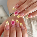 Hand wearing almond flower French press on nails in nude pink and pastel yellow