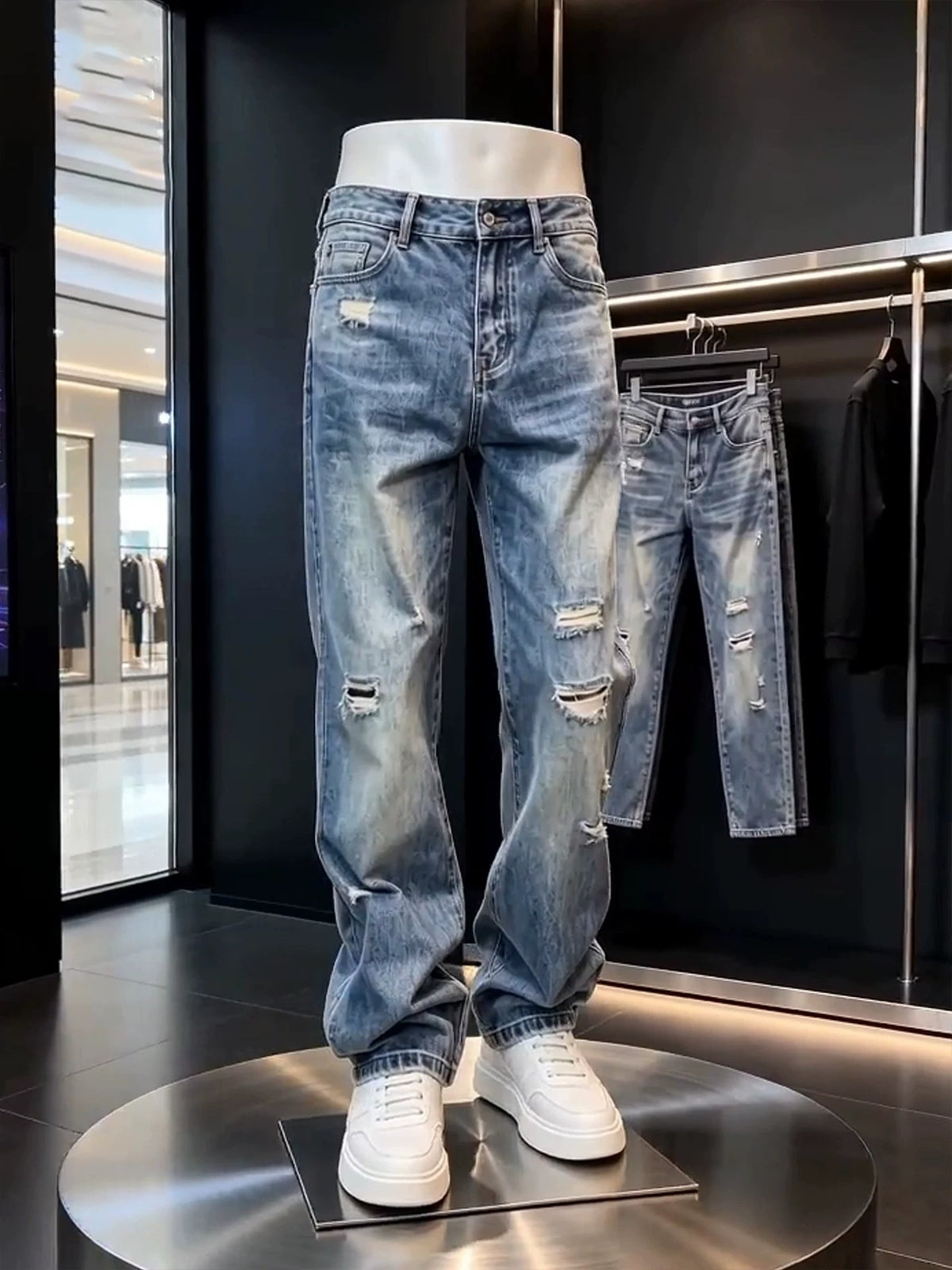 Blue distressed denim jeans with belt loops and a zip fly on a mannequin with white sneakers