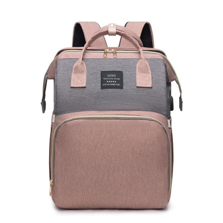 Pink and gray diaper backpack front view with two top handles, a small woven label and a pink front pocket
