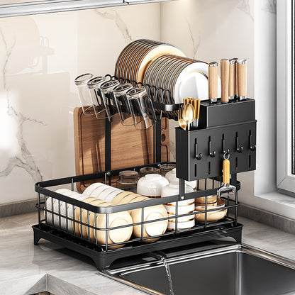 Black two-tier dish rack with plates, glasses, a knife holder and a cutting board beside a kitchen sink