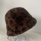 Chocolate brown leopard print plush bucket hat with large spots on a clear stand