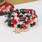 Stack of mixed red, green and white bead stretch bracelets with snowflake and bell charms by a holiday stocking