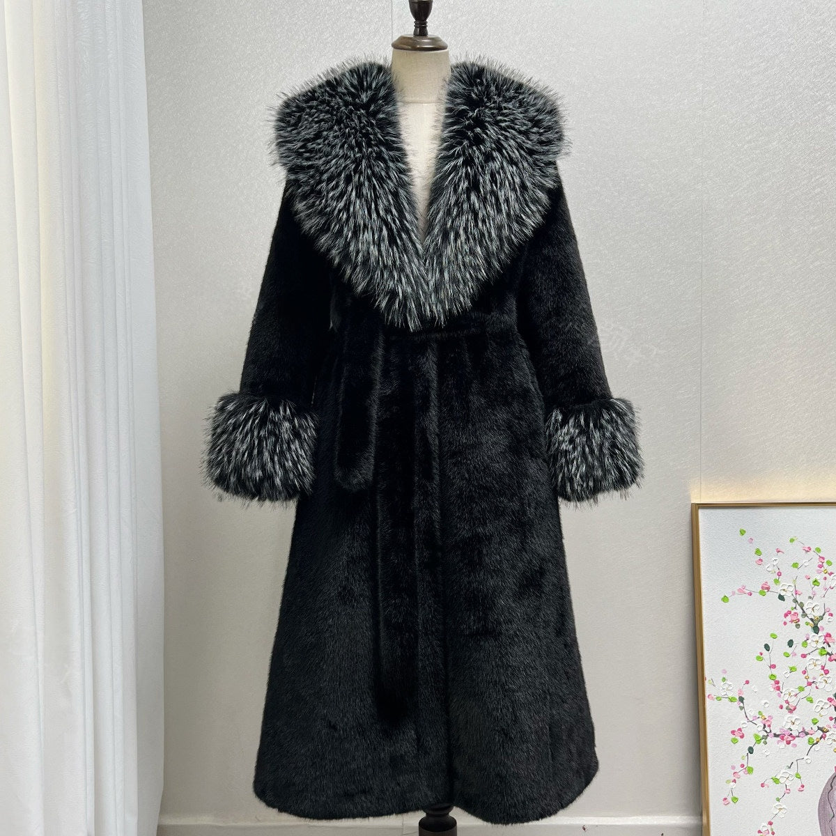 Black long belted vegan fur coat with a silver tipped fur collar and fur cuffs on a mannequin