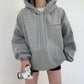 Light gray oversized hooded sweatshirt with drawstrings and a front pouch pocket, a camera held in one hand