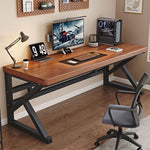 Dark walnut desk with a black K-shaped frame holding a monitor, keyboard and lamp beside a gray office chair