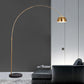 Gold arc floor lamp with a curved arm and round black marble base beside a sofa