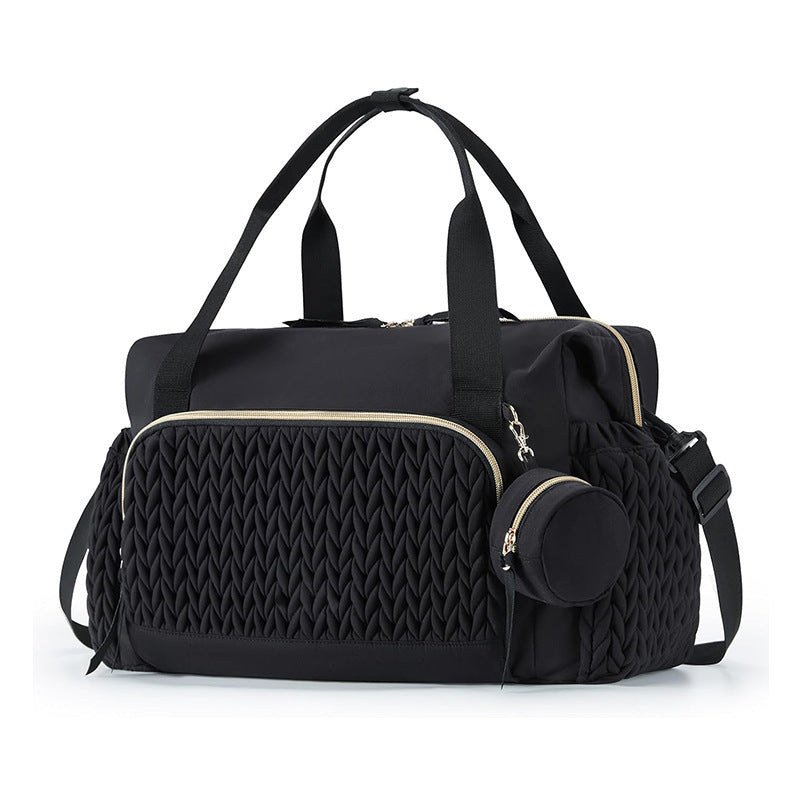Black nylon diaper bag tote with gold tone zips, braided quilt panel and a clip on round pacifier pouch