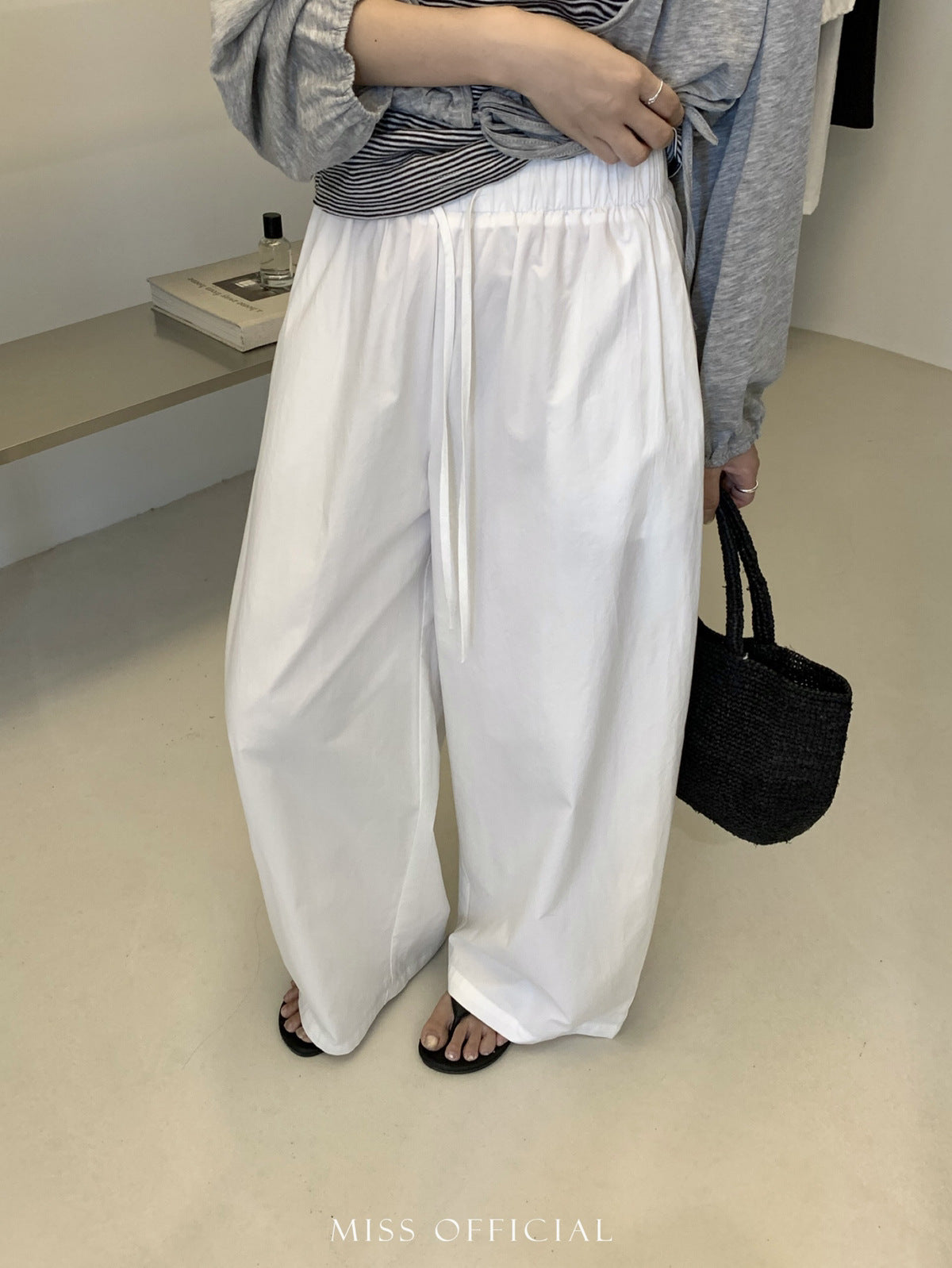 White cotton trousers showing shirred elastic drawstring waist and wide leg