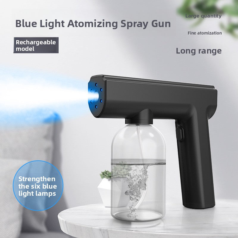 Black handheld blue light atomizing spray gun with a clear liquid bottle spraying fine mist