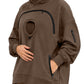 Brown oversized fleece hoodie with a round chest pocket, arched zipper and zipped hand pockets on a woman