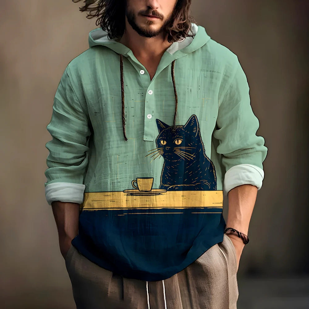 Man wearing a teal hooded henley shirt with a black cat and a coffee cup print