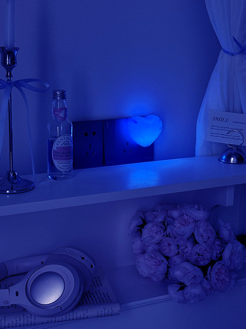Blue heart night light glowing on a shelf in a dark blue lit room