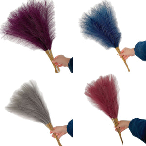 Artificial reed pampas plumes shown in several colors held against a plain background