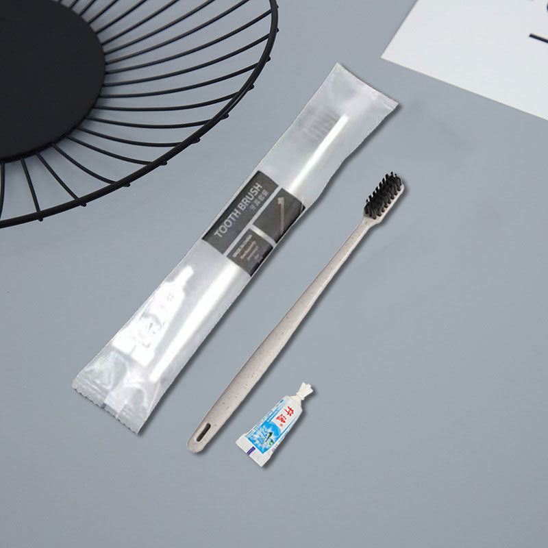 Disposable travel toothbrush and small toothpaste tube with a sealed pouch on a plain surface