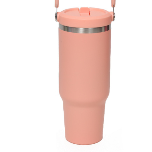 Coral insulated tumbler with a stainless steel ring below the flip lid and a handle at the top