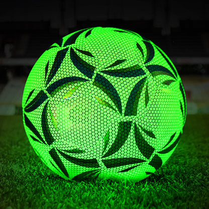 Green glowing fluorescent football on grass at night in a stadium, glow in the dark training ball