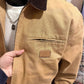 Close view of the khaki jacket chest zip pocket with a small square patch and the dark brown collar