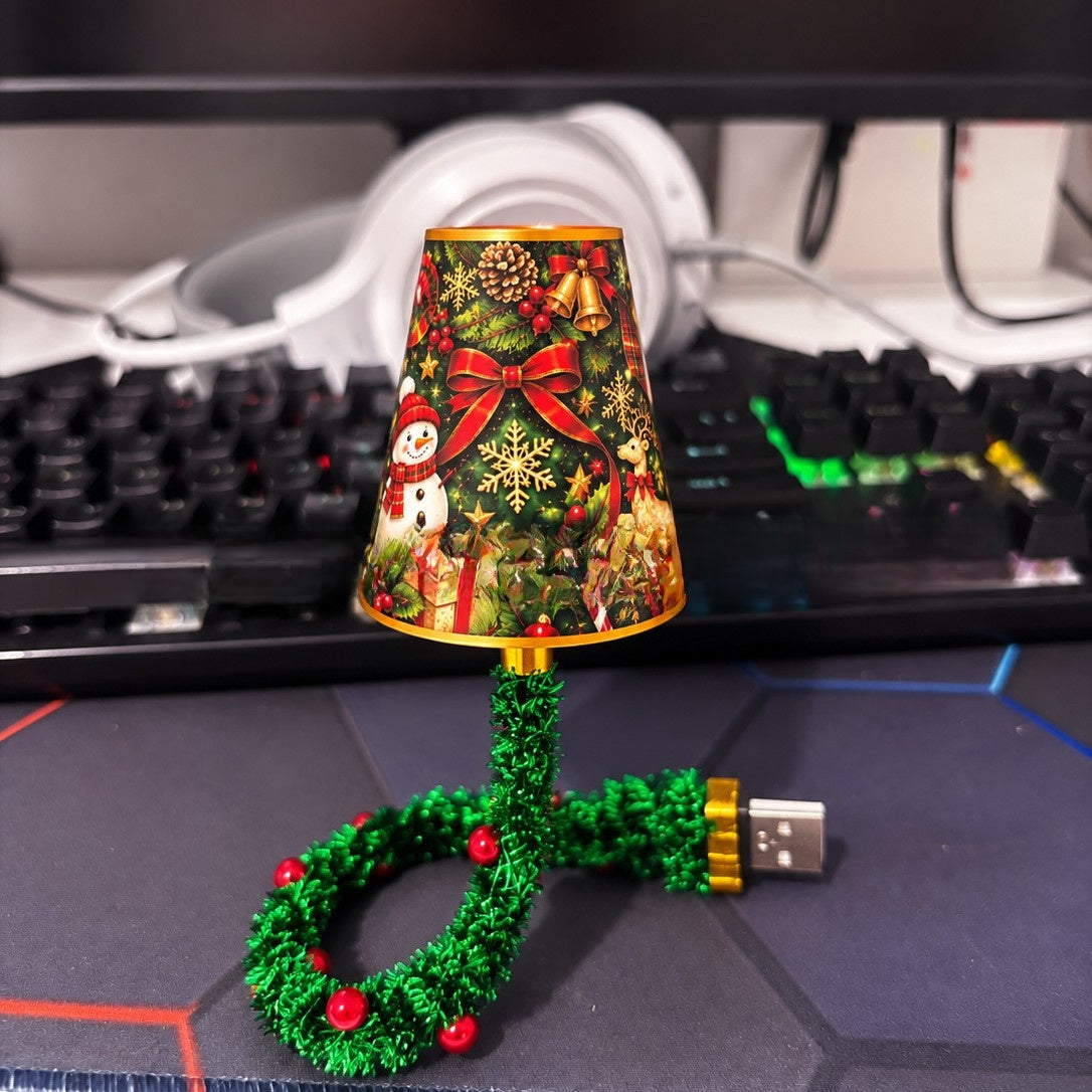 Snowman Reindeer design: Christmas light with a festive printed shade and green tinsel stem plugged in beside a keyboard